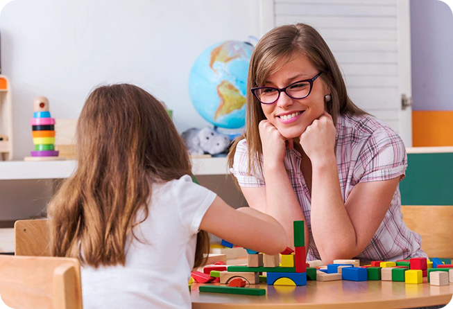 A woman and girl sitting at a table with blocks.