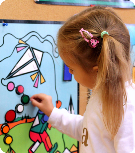 A little girl painting with her hands on the wall.