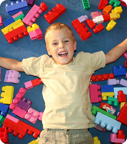 A boy laying on the ground with many toy blocks